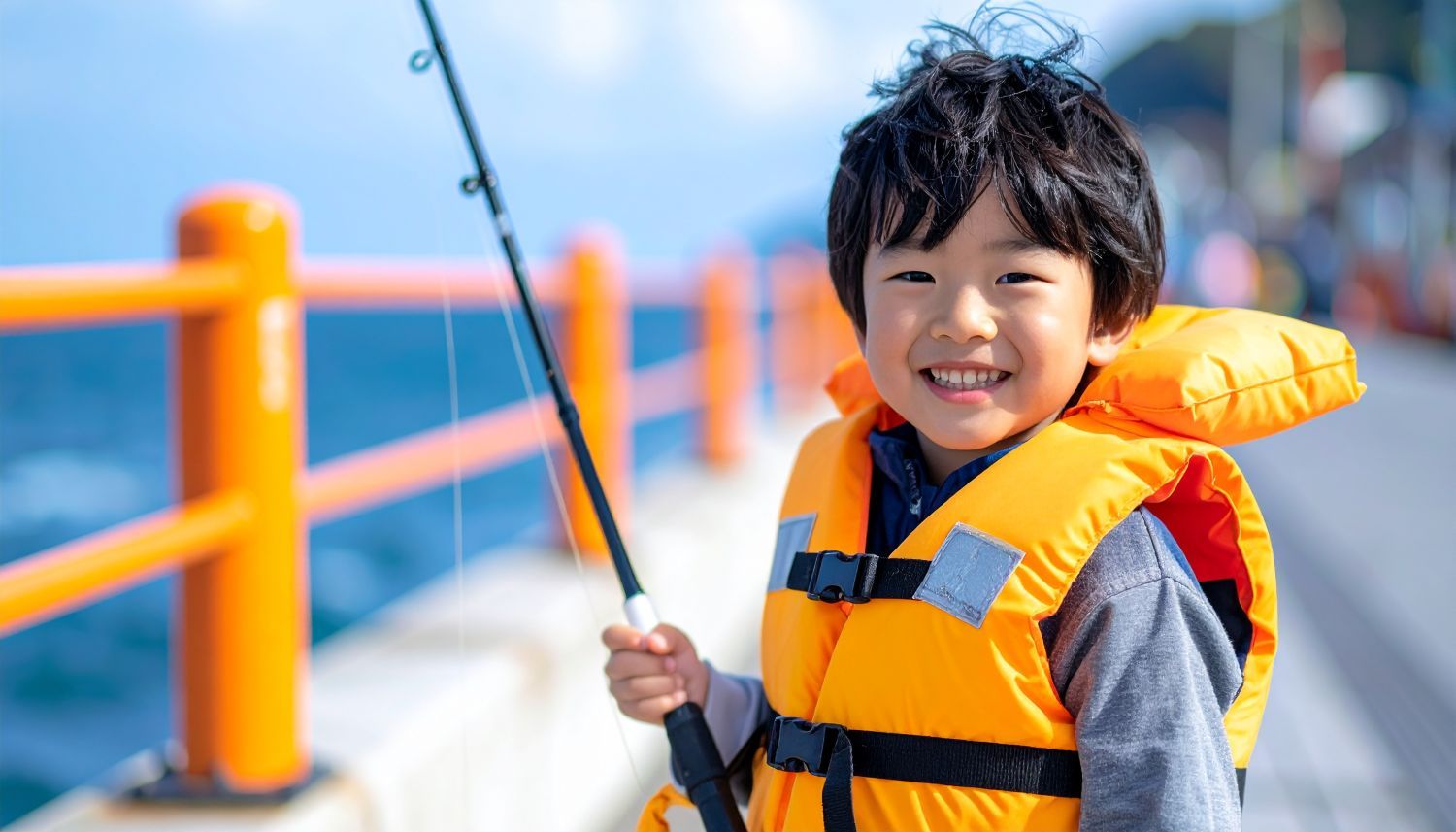 ライフジャケットを着けて堤防で釣りをする子供